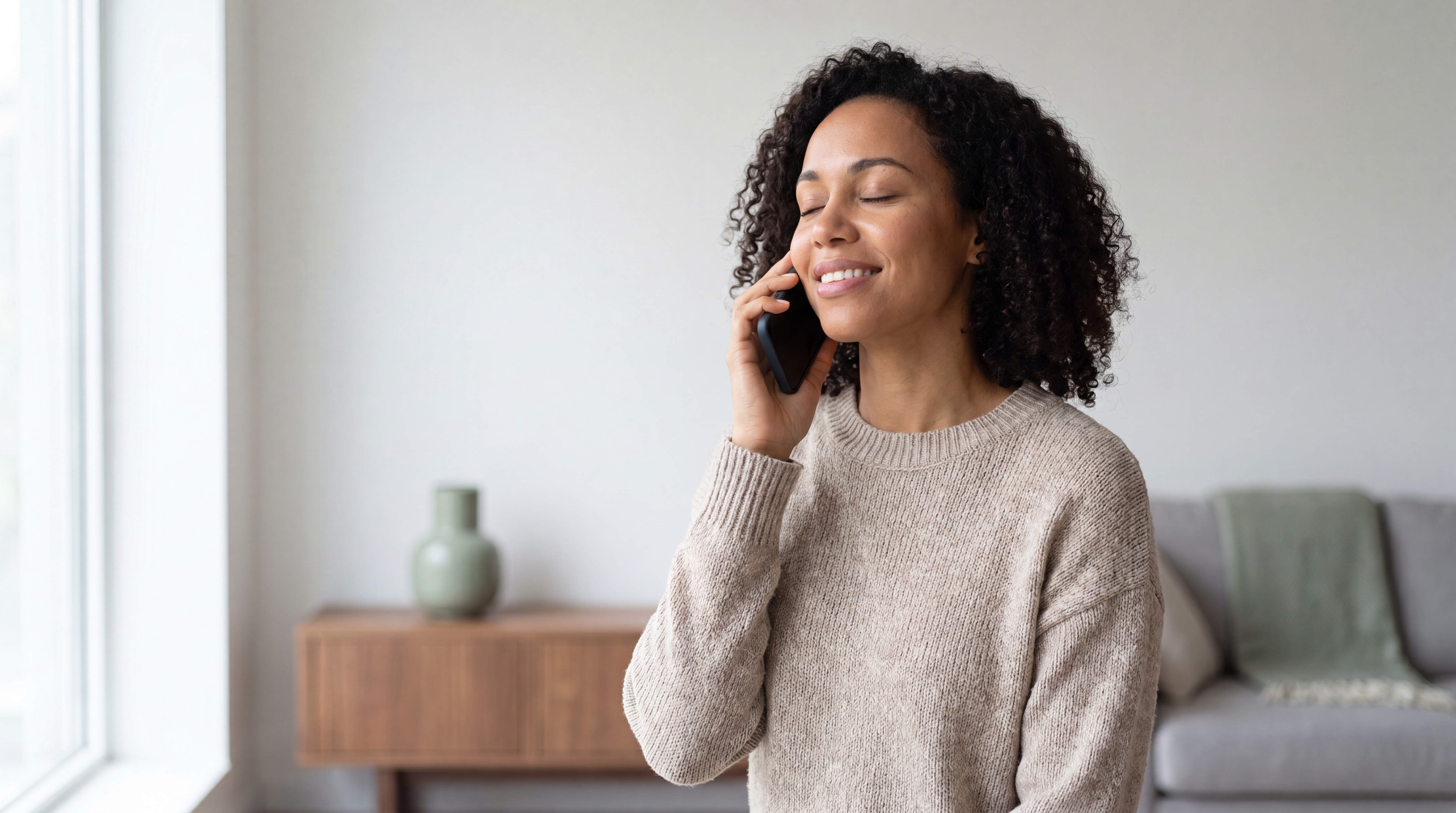 Une femme apaisée, les yeux fermés, au téléphone dans une ambiance calme